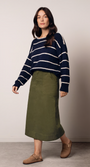 Woman wearing a navy striped sweater and green skirt.