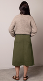 Person wearing a beige sweater and green skirt .