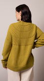 Person wearing a mustard yellow knitted sweater.