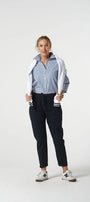 Person wearing a striped shirt, black pants, and white sneakers on a white background