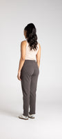Person wearing a beige top and gray pants on a white background