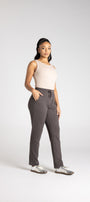 Woman wearing a beige top and gray pants on a white background
