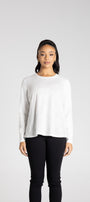 Woman wearing a white long-sleeve top and black pants on a white background