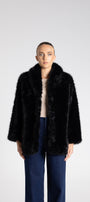 Person wearing a black fur coat on a white background
