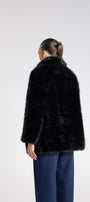 Person wearing a black fur coat on a white background