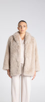 Person wearing a beige fur coat on a white background