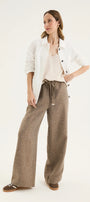 Woman wearing a white blazer and brown pants on a white background