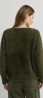 Person wearing a green sweater and pants on a plain background