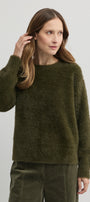 Woman wearing a green sweater against a plain background