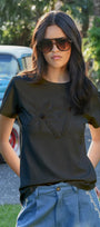 Woman wearing a black t-shirt with a graphic design and sunglasses, standing outdoors.