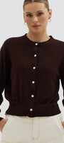 Woman wearing a brown button-up cardigan over a white top with a plain background