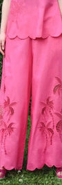 Person wearing a pink pant with floral embroidery against a green background