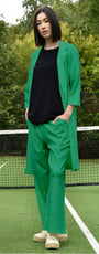 Person wearing a green outfit on a tennis court with trees in the background