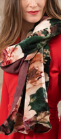 Woman wearing a floral scarf with a red outfit against a neutral background