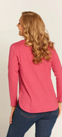 Woman wearing a pink long-sleeve top and blue jeans on a beige background