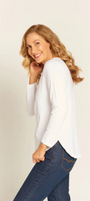 Woman wearing a white blouse and blue jeans against a plain background