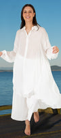 Woman in a white dress standing on a wooden platform by the sea