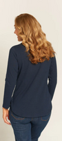 Woman wearing a navy blue long-sleeve top and jeans on a beige background