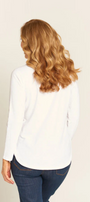 Woman wearing a white blouse and blue jeans against a beige background