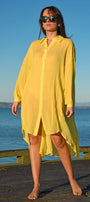 Woman wearing a yellow cover-up on a wooden dock with blue water and sky in the background