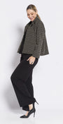 Woman wearing a black and white patterned jacket with black pants on a white background