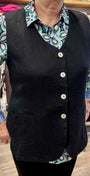 Front view of a black vest over a patterned shirt with visible buttons.