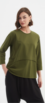 Woman wearing a green top and black pants on a white background