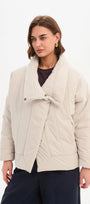 Woman wearing a beige quilted jacket on a white background