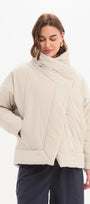 Woman wearing a beige quilted jacket on a white background