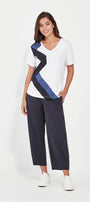 Woman wearing a white t-shirt with blue and black design and navy pants on a white background