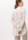 Back View A female model wearing a beige long sleeved shirt with pink and white geometric pattern.